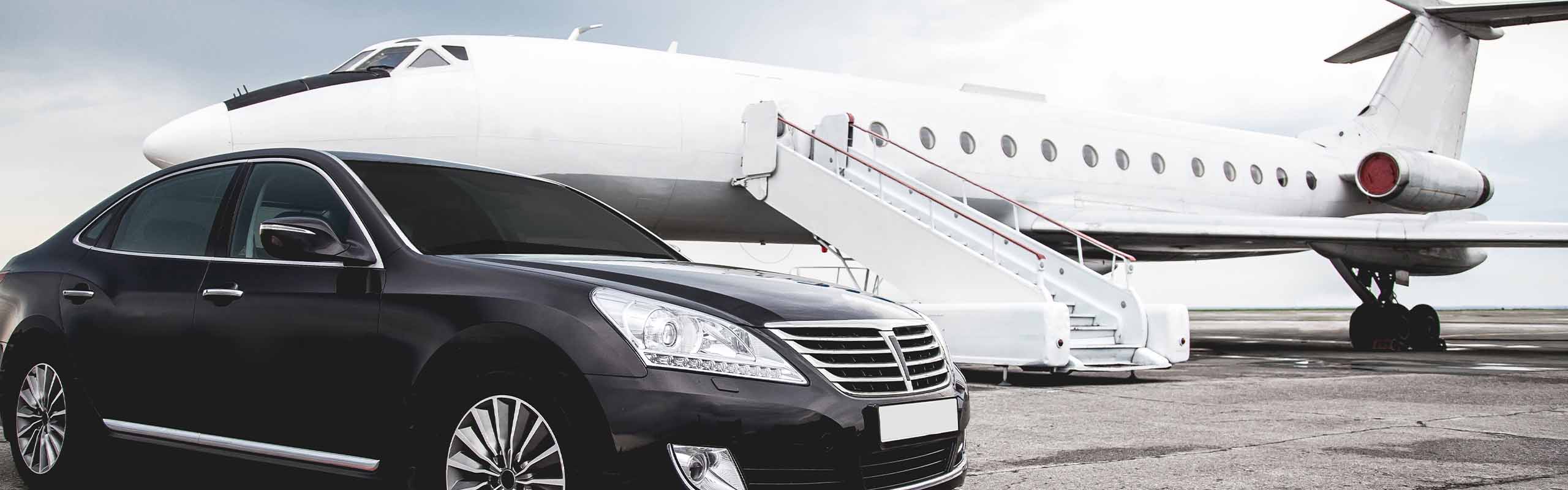 A car in front of a plane on a runway.