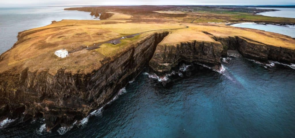 A dramatic drone shot of Dunnet Head Lighthouse in winter.